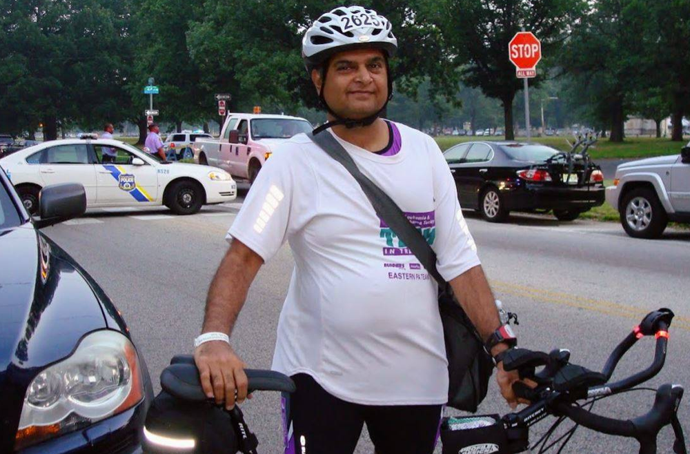 Sanjay Shah wears a helmet and stands next to his bike